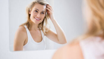 Young woman checking her hair in bathroom mirror at home