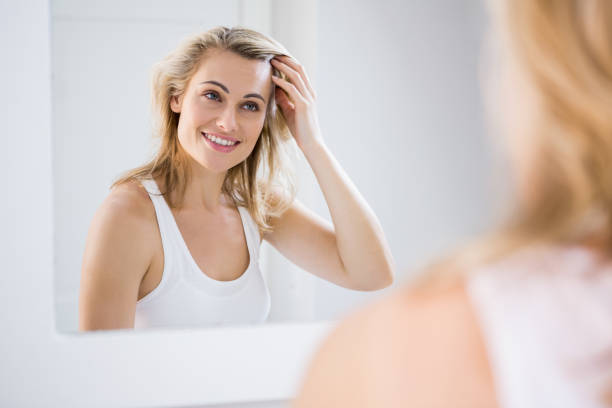 Young woman checking her hair in bathroom mirror at home