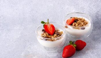 two glass cups with muesli, yogurt, chocolate, fresh strawberries, copy space