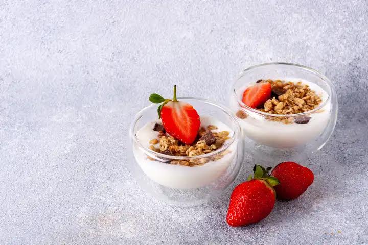 two glass cups with muesli, yogurt, chocolate, fresh strawberries, copy space