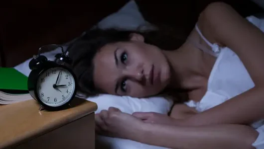 Woman in her 40s experiencing perimenopause insomnia, lying awake in bed with a worried expression